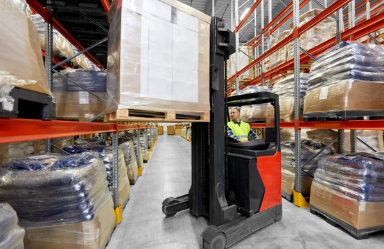 logistic business, shipment and loading concept - loader operating forklift with cargo at warehouse