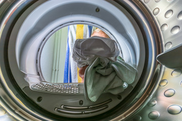 Blick aus einer Waschtrommel die mit dreckiger Wäsche beladen wird