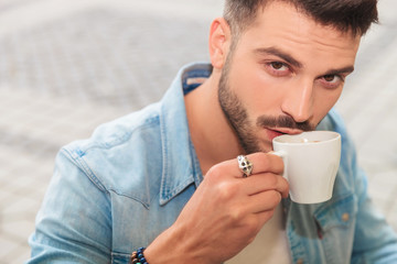 handsome man in shirt drinking coffee outside