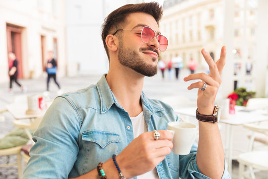 portrait of proud man with sunglasses having a coffee outside