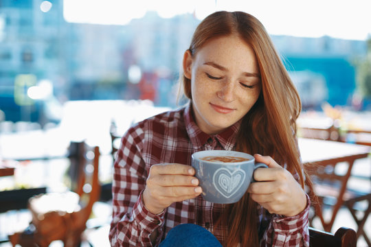  Young woman looking to a cup of coffee smiling