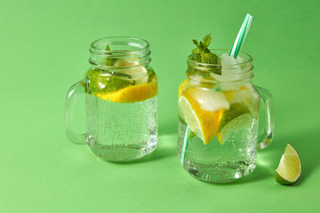 Summer refreshing drink on a green background. Homemade sparkling cocktail in glass jars. Concept of cold alcoholic or non-alcoholic summer drinks.