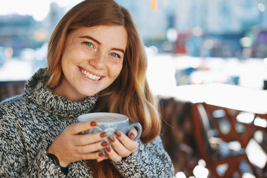 Close-up of natural reddish girl holding a big cup of coffee sho