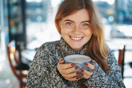 Close-up of reddish natural girl holding a cup of coffee