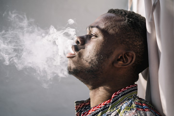 African man smoking white smoke hookah.