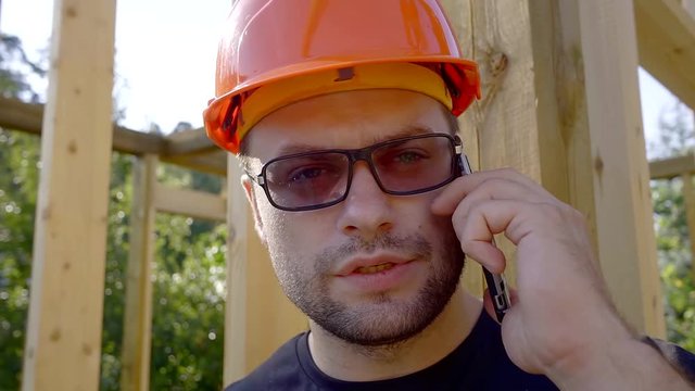 Close Up Shot Of A Contruction Worker Talking On The Phone On The Site.