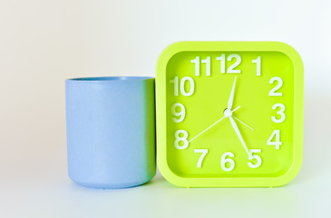 plastic Mug and green square clock isolated on bright background. selective focus.