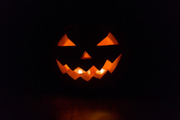 Fototapeta premium halloween and holidays concept - spooky jack-o-lantern or carved pumpkin lantern burning in darkness
