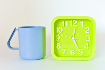 plastic Mug and green square clock isolated on bright background. selective focus.