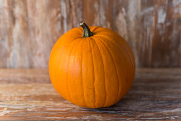 vegetables, harvest and thanksgiving concept - ripe pumpkin on wooden background