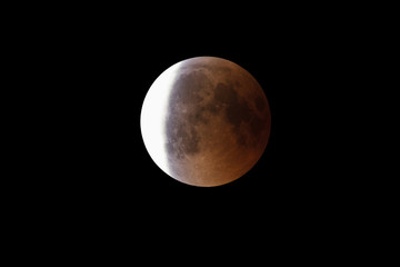 Super Bloody Moon, full eclipse end phase against black sky background, three-quarters of the Moon surface covered by Earth's shadow