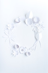 Round frame with white paper flowers on white background.