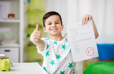 childhood, education and people concept - happy smiling boy holding school test with a grade showing thumbs up