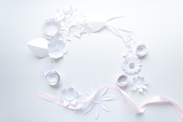 frame with white paper flowers and pink ribbon on white background. Cut from paper.