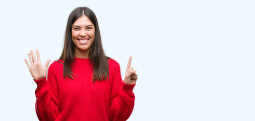 Young beautiful hispanic wearing red sweater showing and pointing up with fingers number six while...