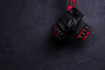 Gloves for MMA hang on nail on a black texture wall.