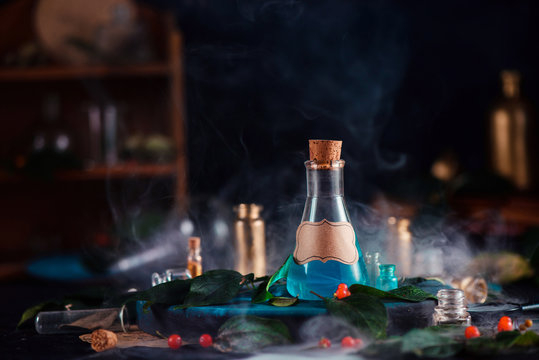 Blank label on a magic potion bottle. Modern witchcraft concept with potions, berries, herbs and occult equipment. Magical still life with copy space on a dark background.
