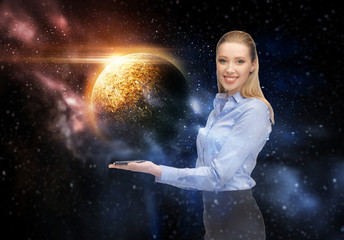 Obraz na płótnie Canvas business, future technology and people concept - smiling businesswoman with smartphone and planet hologram over space background