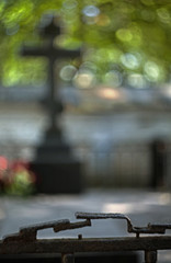 Blurred grave cross with old metal fence on the blurred background at midnight time