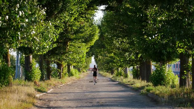 Beautiful Girl In A Black Sport Suit, Runs Along The Road In A Park