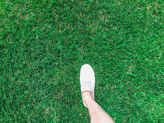 one feet in white sneakers on the grass