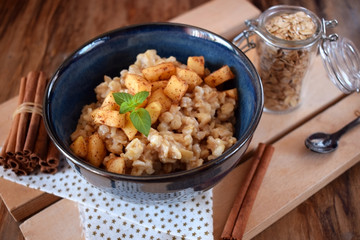 Porridge with apples and cinnamon topped with mint in a blue bowl. British cuisine meal