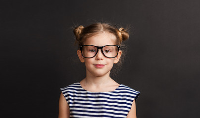 Back To School Concept, Cute Schoolgirl in big eyeglasses. Over black background.