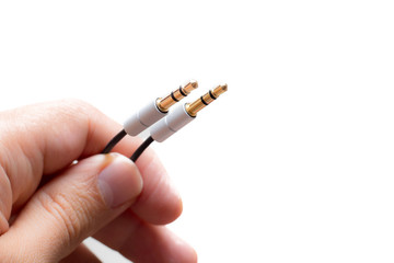 Hand with two stereo audio cable gold coated isolated on white background
