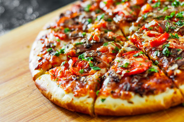 sliced Pizza with Mozzarella cheese, mushrooms, Tomatoes, pepper, Spices and Fresh Basil. Italian pizza.