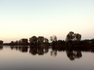 Fototapeta na wymiar Quiet and Calm Sunset Lake Landscape with Trees Reflecting in Tranquil River