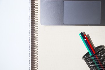 Modern laptop and colorful pencils in holder on light wooden table. Back to school concept