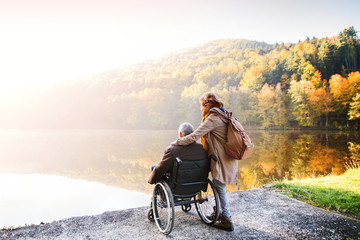 Senior couple with wheelchair in autumn nature.