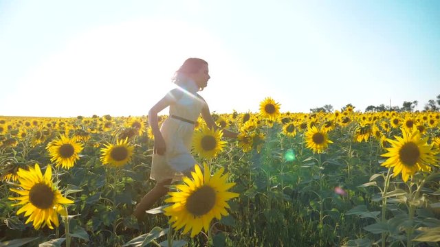 Happy little girl running happy free across the field with sunflowers. lifestyle slow motion video . smelling big sunflower on summer field. Delight of a pleasant smell. Summer holiday. concept
