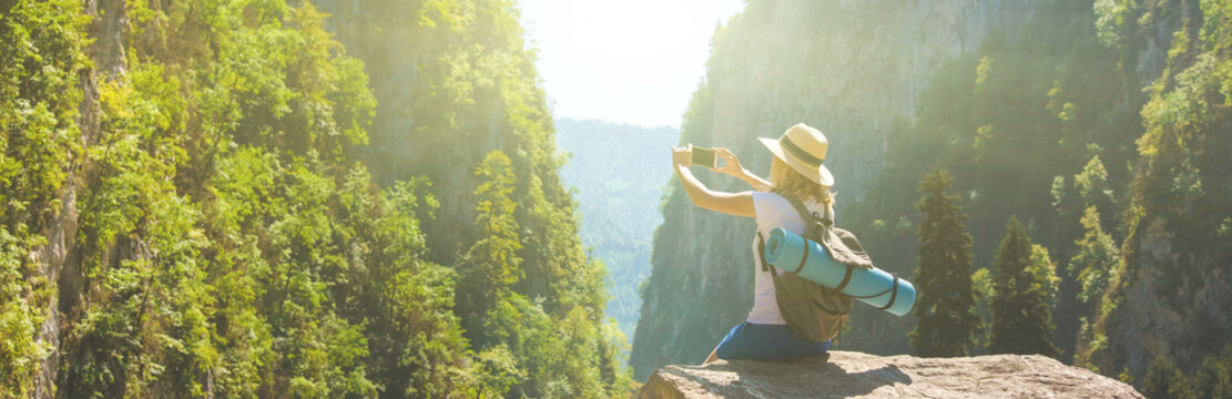 Girl hipster traveler takes pictures of nature on the background of mountains Tourist traveler on background valley landscape view mockup
