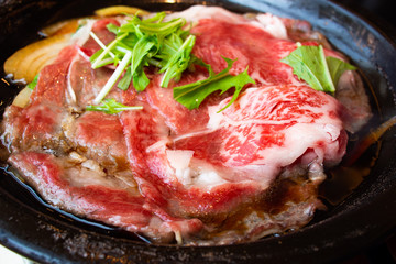 Tasty and delicious Japanese Sukiyaki nabe with best-quality cuts of thinly sliced sirloin or rib eye or tenderloin Kuroge Wagyu beef in a cast iron pan. Good Marble Score. Natural light. Close up.