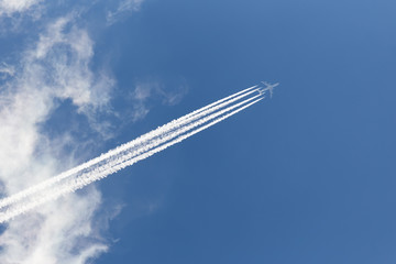 Airplane in cloudy sky with an inverse trace