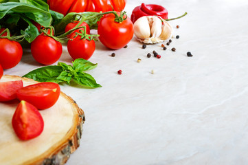 Fototapeta na wymiar Cherry tomato branch, garlic, fresh basil, pepper on a light background. Ingredients for making sauces. Italian Cuisine. Free space for your project.