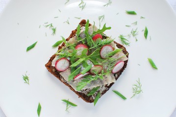 Top view of Danish open sandwich smorrebrod with herring, radish, arugula.