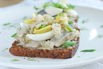 Traditional Danish recipe rye bread open sandwich smorrebrod. Sandwich with herring, boiled egg, onion.