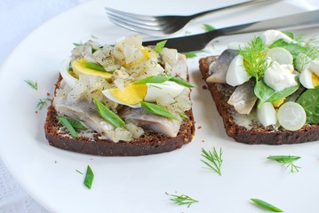 Traditional Danish dark bread open sandwich. Smorrebrod with herring, boiled egg snd herbs.