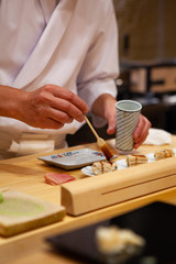 Professional and experienced sushi chef carefully add final touch with confident and dedication to...