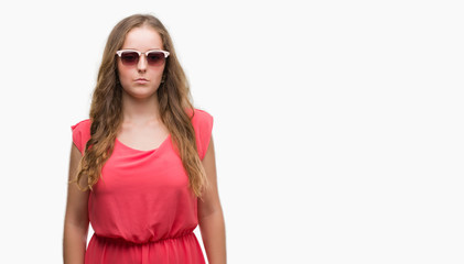 Young blonde woman wearing pink sunglasses with a confident expression on smart face thinking serious