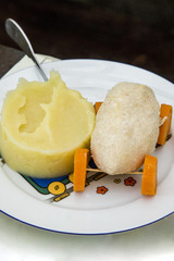 Children's menu, a steamed cutlet in the form of a car on the wheels of boiled carrots and mashed potatoes on a children's plate with a fork.