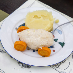 Children's menu, a steamed cutlet in the form of a car on the wheels of boiled carrots and mashed potatoes on a children's plate with a fork.