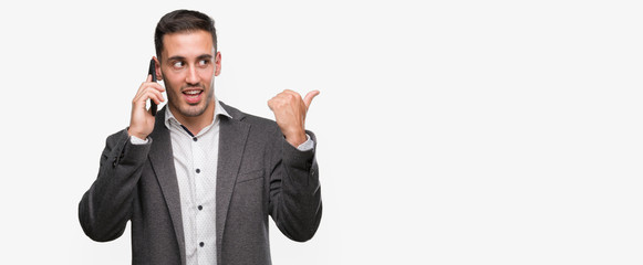 Handsome young man using smartphone pointing with hand and finger up with happy face smiling