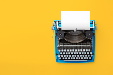 Typewriter machine in retro style on yellow background. Top view. - obrazy, fototapety, plakaty