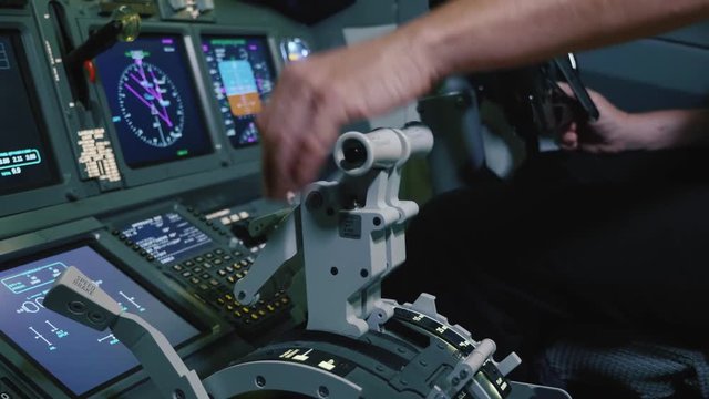 Pilot holding hand on the thrust lever handle for engine control of airliner.