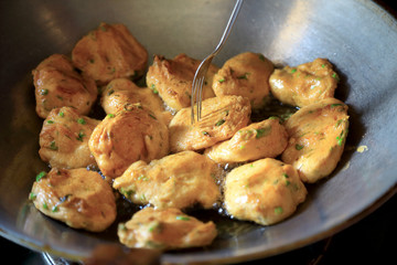 Fried fish cakes or patty, in the pans background with hot oil and the fork, Thai foods concept.