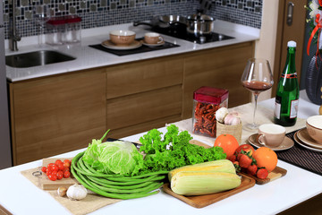 Fresh organic vegetables on white counter bar table background in kitchen. with Lettuces, Chinese cabbage, Yard long beans, Cherry tomato, Dried garlic, Orange, Strawberries, Wine glass,