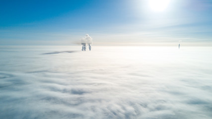 Photo of smoking pipes from a drone flying through the clouds, over the fog